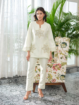 This elegant top is tailored in rich silk fabric, blending timeless allure with a modern edge. The front is adorned with intricately embroidered floral motifs, delicately rendered in golden zari and enhanced with fine hand-embellished kadhana work for depth and dimension. The embroidery extends gracefully along the sleeves, creating a seamless flow of artistry and balance. A perfect expression of classic charm reimagined through contemporary elegance, this piece is designed for effortless sophistication.
