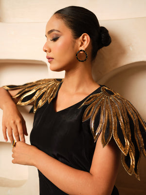 Crafted in premium Natural Crepe, this designer co-ord set features stunning cape-inspired cutwork shoulders adorned with pure hand embroidery, golden metallic sali, and kadhana work. Paired with matching flared trousers, it is a perfect blend of contemporary elegance and artisanal craftsmanship for festive and occasion wear.