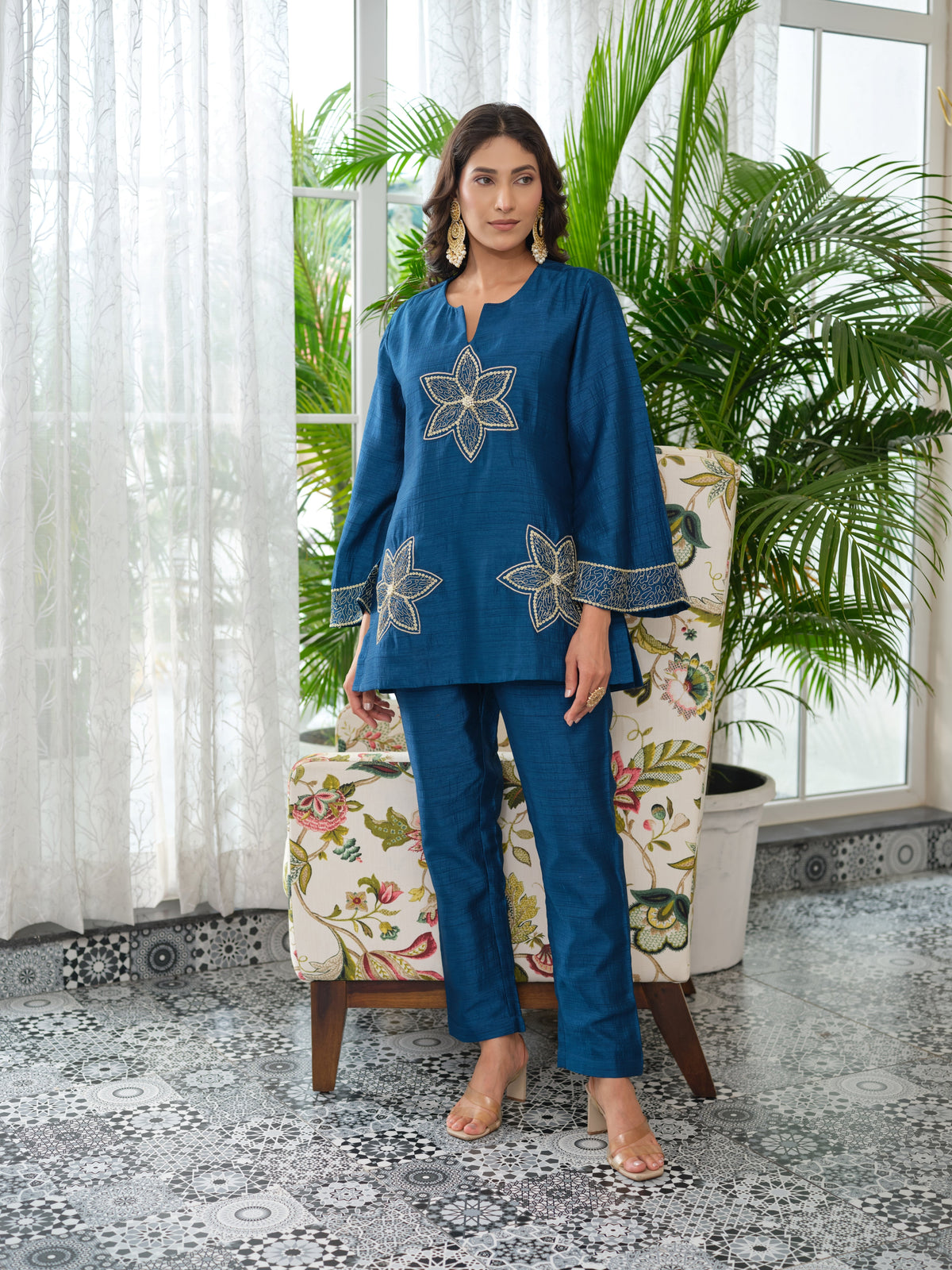 This elegant top is tailored in rich silk fabric, blending timeless allure with a modern edge. The front is adorned with intricately embroidered floral motifs, delicately rendered in golden zari and enhanced with fine hand-embellished kadhana work for depth and dimension. The embroidery extends gracefully along the sleeves, creating a seamless flow of artistry and balance. A perfect expression of classic charm reimagined through contemporary elegance, this piece is designed for effortless sophistication.