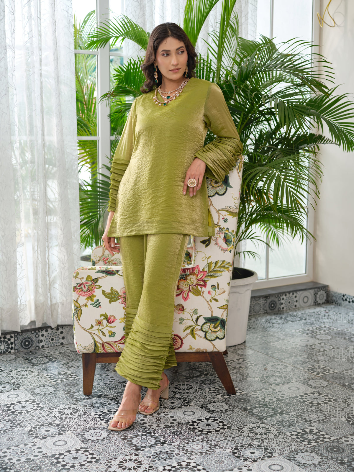 This elegant top is crafted from soft crush organza fabric in a beautiful pistachio green shade. Lightweight and delicately textured, the fabric offers a subtle sheer finish that adds a touch of luxury and modern sophistication. The design features a relaxed, flowy silhouette that blends comfort with effortless grace. Dramatic pleated detailing on the sleeves creates beautiful movement and dimension, lending the piece a structured yet fluid appeal. Finished with a minimal V-shaped neckline.