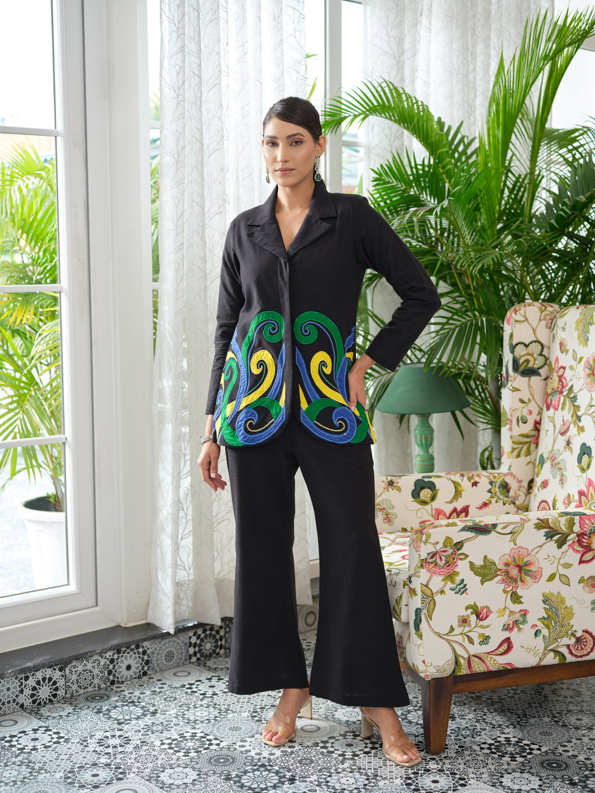 Crafted in cotton handloom fabric, this shirt features intricate appliqué work in vibrant pink, blue, and orange swirls, enhanced with delicate hand embroidery and silver cut and pearl detailing. Designed with a tailored silhouette, it blends artisanal craftsmanship with effortless sophistication.