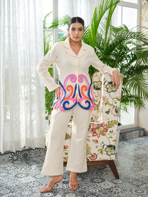 Crafted in cotton handloom fabric, this shirt features intricate appliqué work in vibrant pink, blue, and orange swirls, enhanced with delicate hand embroidery and silver cutdana pearl detailing. Designed with a tailored silhouette, it blends artisanal craftsmanship with effortless sophistication.