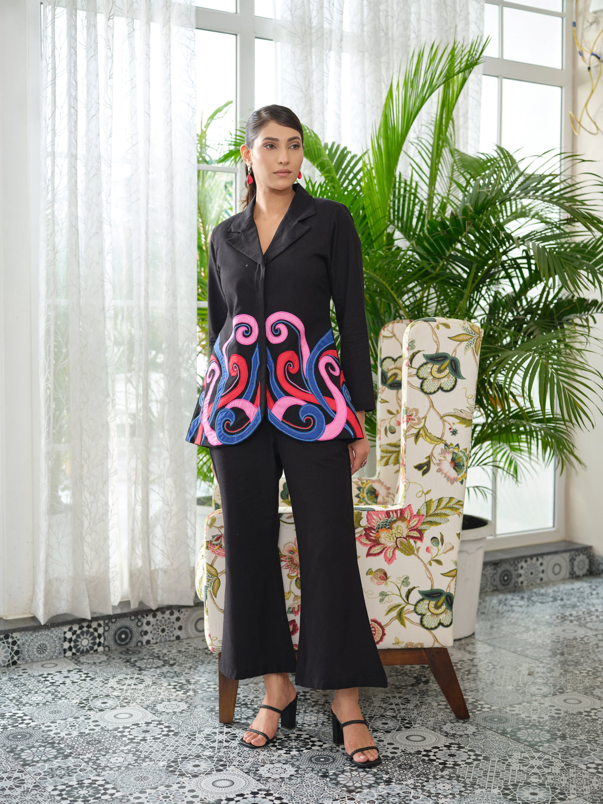 Crafted in cotton handloom fabric, this shirt features intricate appliqué work in vibrant pink, blue, and orange swirls, enhanced with delicate hand embroidery and silver cutdana pearl detailing. Designed with a tailored silhouette, it blends artisanal craftsmanship with effortless sophistication.